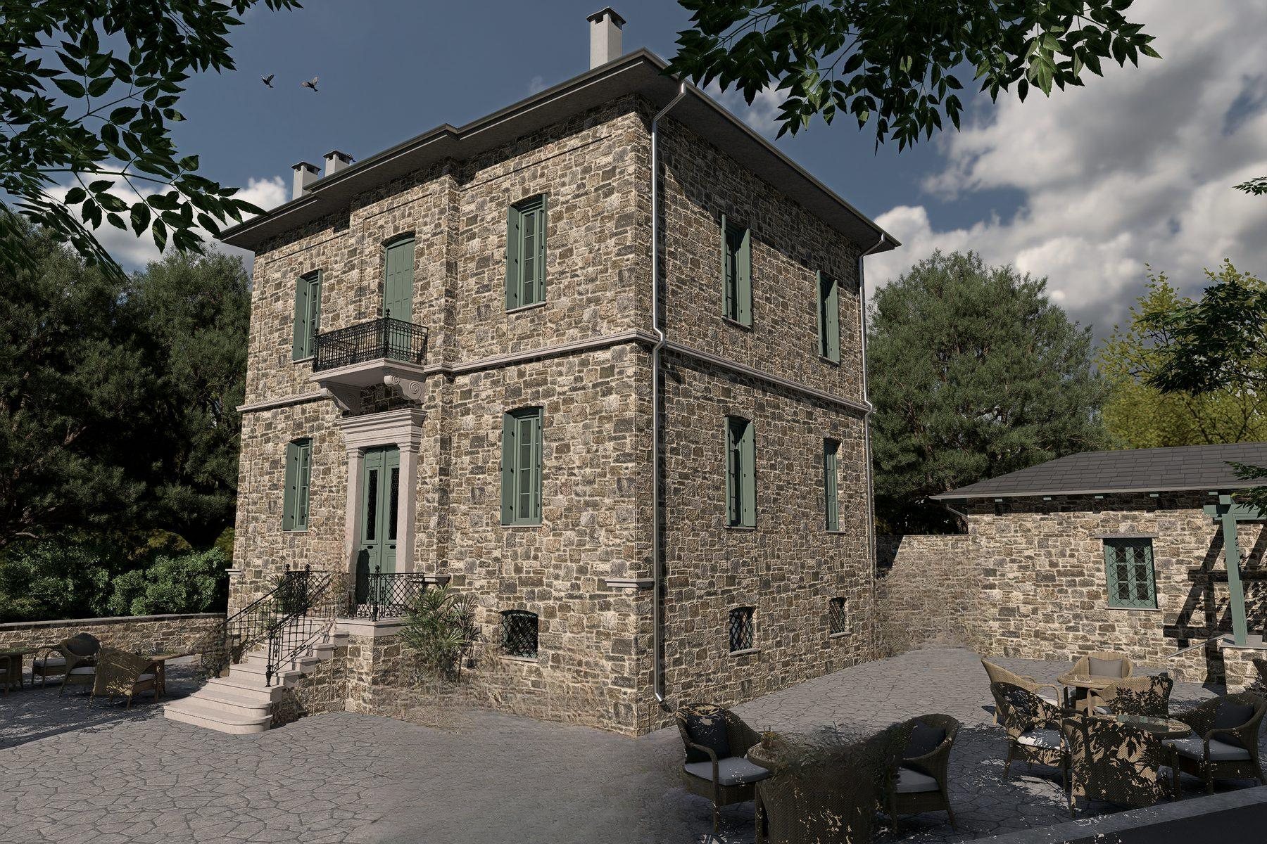 The front facade of the stone mansion, with green shutters and a stone stair to the door