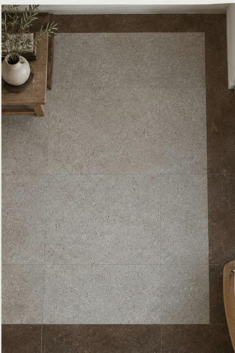 Grey stone floor tiles with a dark brown border and a jute rug